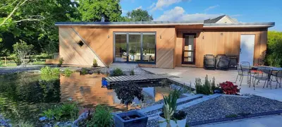 a small house with a pond in front of it at Mid-Wales Farmhouse, swimming pool, tranquil countryside views, sleeps 14 in Meifod