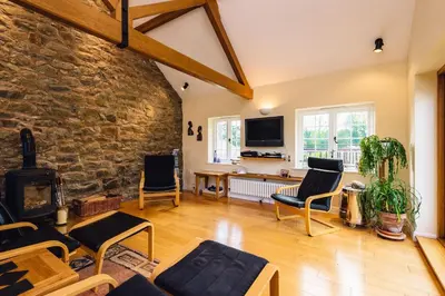 a living room with a stone wall and a tv at Mid-Wales Farmhouse, swimming pool, tranquil countryside views, sleeps 14 in Meifod