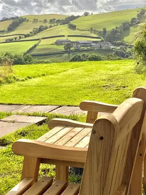 a wooden bench sitting on top of a green field at Garden Room near Brecon in Brecon