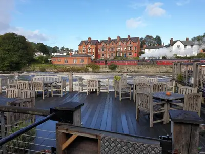 a deck with tables and chairs and a building at 8 Opera Suites, Llangollen in Llangollen