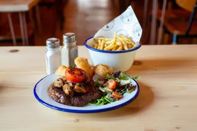 a plate of food with a steak and salad and a bowl of fries at Hampton Hotel & restaurant in Llandrindod Wells