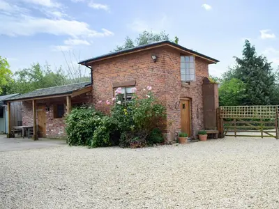 a brick house with a fence in front of it at Pepperpot Lodge in Baschurch