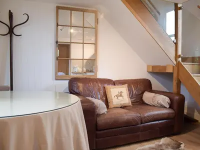 a brown leather couch in a living room with a table at Pepperpot Lodge in Baschurch