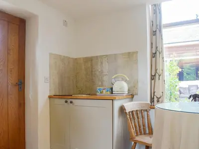 a kitchen with a counter and a chair and a window at Pepperpot Lodge in Baschurch