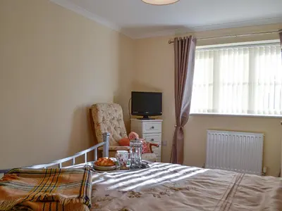 a bedroom with a bed and a chair and a television at Penmaen in Talgarth