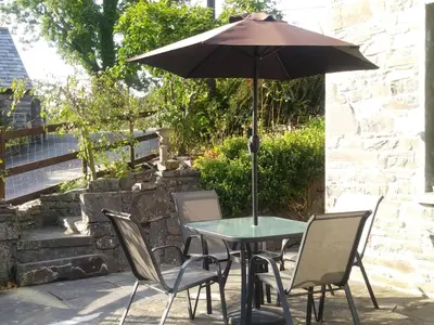 a table and chairs with an umbrella on a patio at Mill Cottage in Llanddeiniol