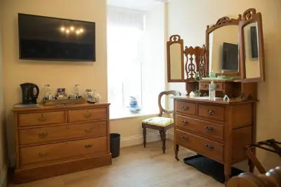 a bathroom with a wooden dresser and a mirror at The Royal in Barmouth