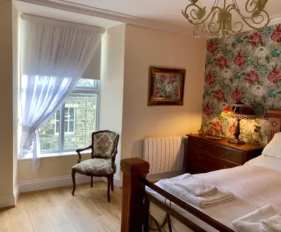 a bedroom with a bed and a chair and a window at The Royal in Barmouth