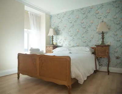 a bedroom with a large bed with floral wallpaper at The Royal in Barmouth