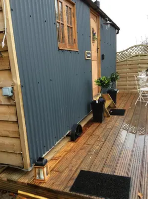 a deck with a blue wall and a building at Llangollen Shepherds Huts in Llangollen