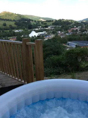 a hot tub on a deck with a view at Llangollen Shepherds Huts in Llangollen