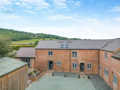 an exterior view of a brick house with a courtyard at Y Stabl - Uk12742 in Acrefair