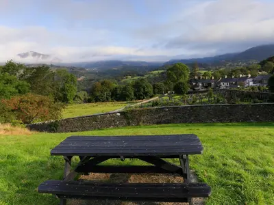 a wooden bench sitting in a field with a view at Moelwyn View Cottage in Blaenau-Ffestiniog