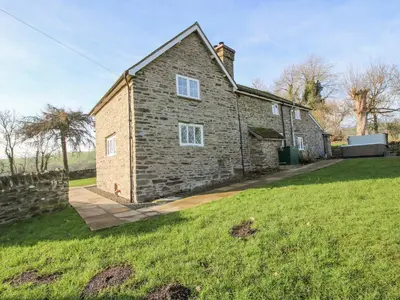 a stone house in a field with a grass yard at Little Bicton in Craven Arms