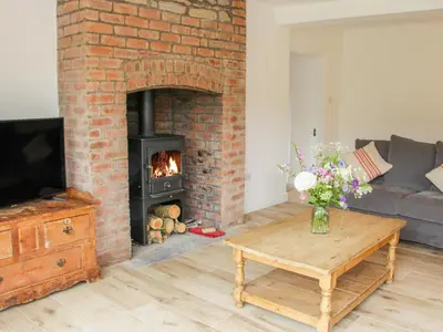 a living room with a brick fireplace and a table at The Old Farmhouse, Upper Pitts in Knighton
