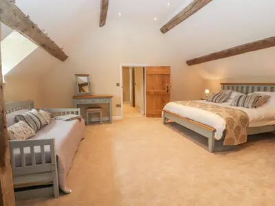 a attic bedroom with two beds and a table at Rhandregynwen Hall in Llanymynech