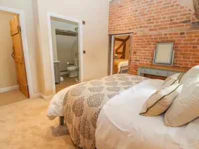 a bedroom with a brick wall and a bed at Rhandregynwen Hall in Llanymynech