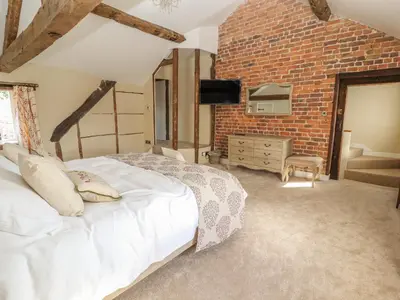 a bedroom with a white bed and a brick wall at Rhandregynwen Hall in Llanymynech