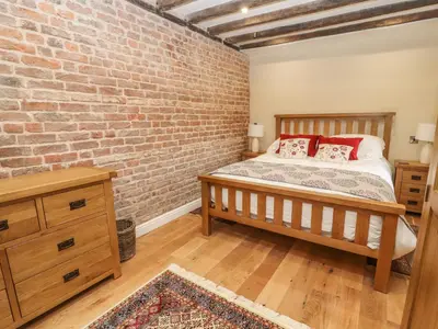 a bedroom with a brick wall and a bed at Rhandregynwen Hall in Llanymynech