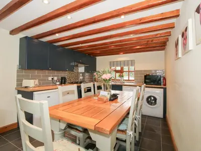a kitchen with a wooden table and some chairs at Old Hall Barn 3 in Church Stretton