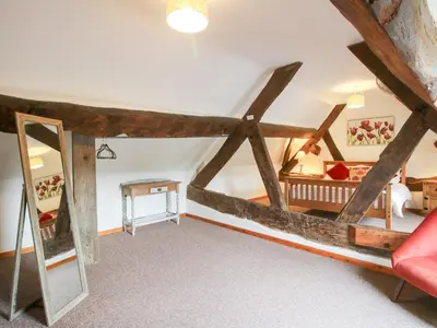a living room with a red couch and a bed at Old Hall Barn 3 in Church Stretton