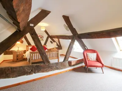 a room with wooden beams and a red chair at Old Hall Barn 3 in Church Stretton
