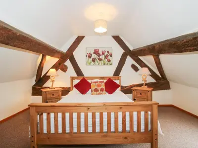 a bedroom with a wooden bed with red pillows at Old Hall Barn 3 in Church Stretton