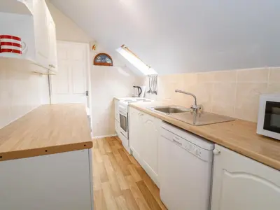 a white kitchen with a sink and a counter at Abermaw Views in Barmouth
