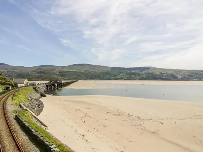 a beach with a bridge and a body of water at Abermaw Views in Barmouth
