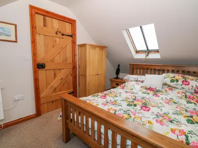 a bedroom with a bed and a wooden door at Dysynni in Tywyn