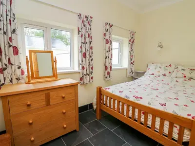 a bedroom with a bed and a dresser and a mirror at Hen Brynbedw in Llanybydder