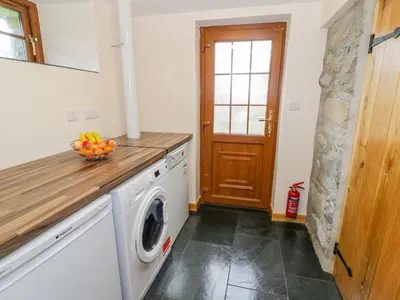 a kitchen with a washing machine with a bowl of fruit at Yr Hen Stabal in Blaenau-Ffestiniog