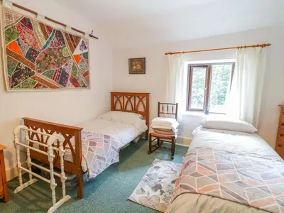 a bedroom with two beds and a window at Dyfi Cottage in Machynlleth