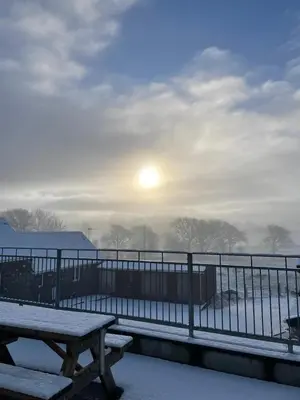 a picnic table in the snow with the sun in the background at Ffyllon Fawr in Henfynyw Upper