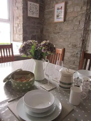 a table with plates and a vase with flowers on it at Ffyllon Fawr in Henfynyw Upper