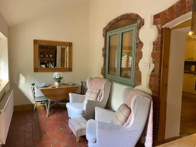 a living room with two chairs and a table at Romantic Cottage with Wood-fired Hot tub and Outdoor Pizza Oven in Shrewsbury