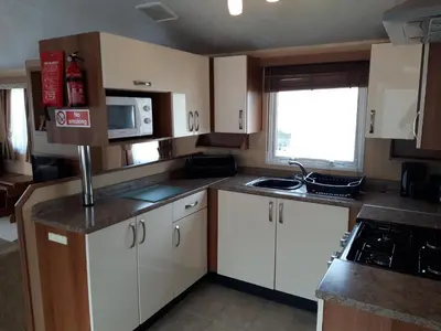 a small kitchen with white cabinets and a window at Clwyd 6 in Borth