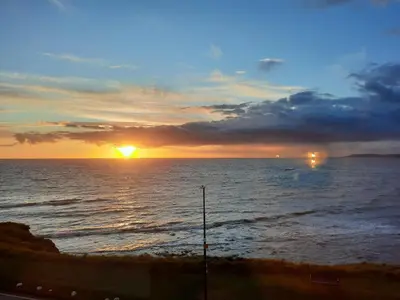 a sunset over the ocean with the sun setting at Cliff haven in Borth
