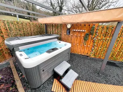 a hot tub sitting on a bench next to a fence at Private Heated Bedrooms at The Bunkhouse in Snowdonia Perfect for Bikers and Walkers in Dolgellau