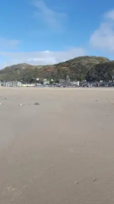 a sandy beach with houses and mountains in the background at Hendre Coed Isaf static caravan Barmouth in Barmouth
