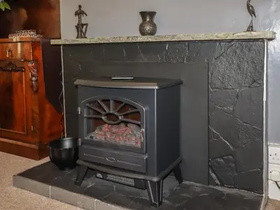 a black stove in a room with a stone wall at Sunningdale in Ludlow