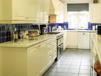 a white kitchen with white cabinets and blue tiles at Sunningdale in Ludlow