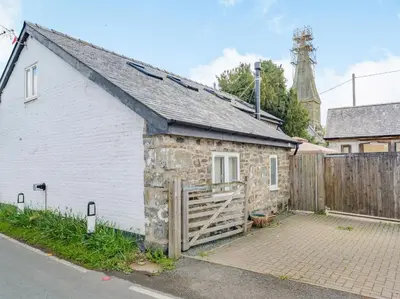 a small white building with a wooden gate at Yew Tree Cottage in Welshpool