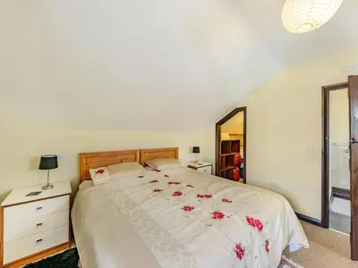 a bedroom with a large white bed with flowers on it at Yew Tree Cottage in Welshpool