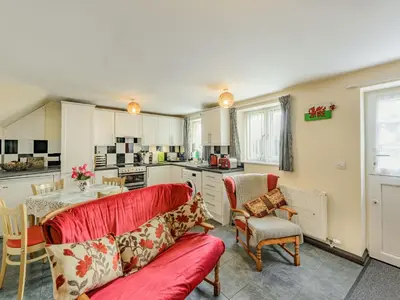 a living room with a red couch and a kitchen at Yew Tree Cottage in Welshpool
