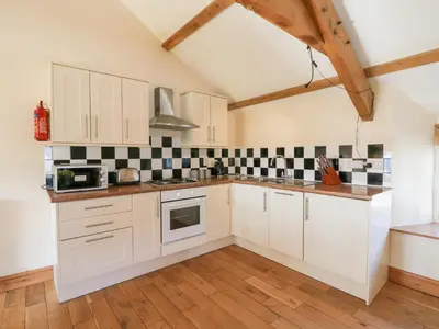 a kitchen with white cabinets and black and white tiles at The Stable in Lampeter