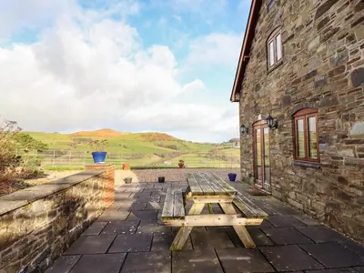 a picnic table on the patio of a stone building at The Old House in Llanidloes