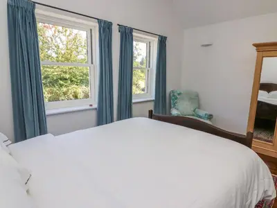 a bedroom with a white bed and two windows at The Pheasantry in Builth Wells