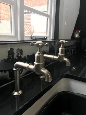 a bathroom sink with two faucets on a black counter at 