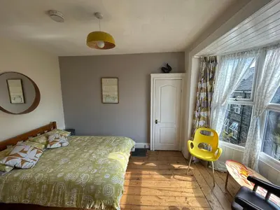 a bedroom with a bed and a yellow chair at Central Barmouth Town House - Near Beach - Sleeps up to 16! in Barmouth